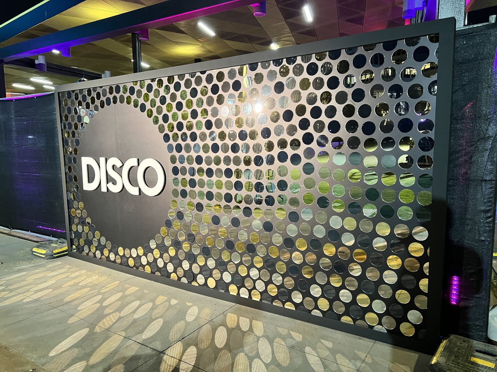 Mirrored disco wall with cut-out circles casting light patterns
