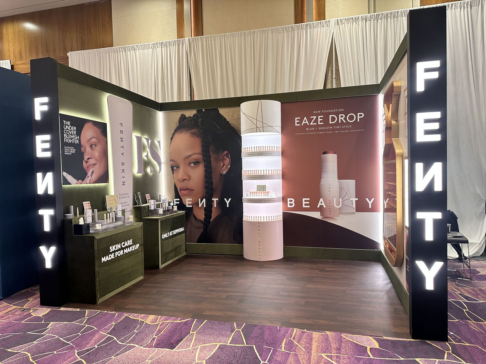 Illuminated branded beauty booth with lightbox pillars and product displays
