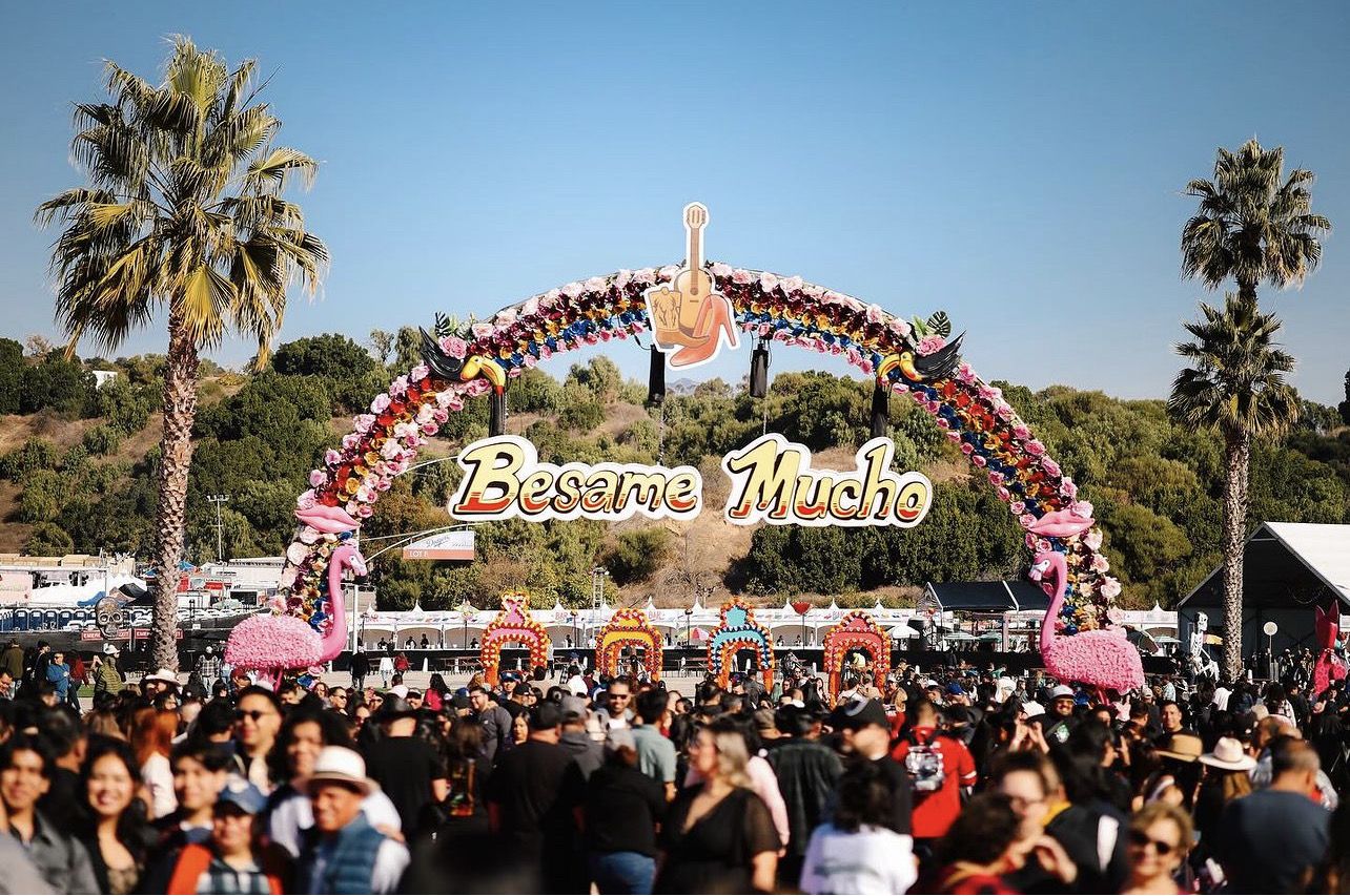 Floral festival archway above a large crowd under palm trees